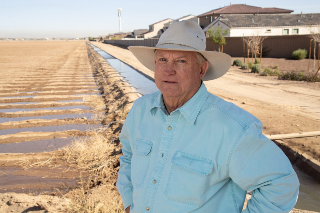 Stephen H. Williams stands beside an irrigation canal in Laveen, Arizona, highlighting agricultural water management and the impact of local development on farmland.